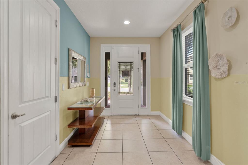 A bright entryway features tile flooring, a console table, and a white front door — 7613 BROOKHURST LANE, KISSIMMEE, FL