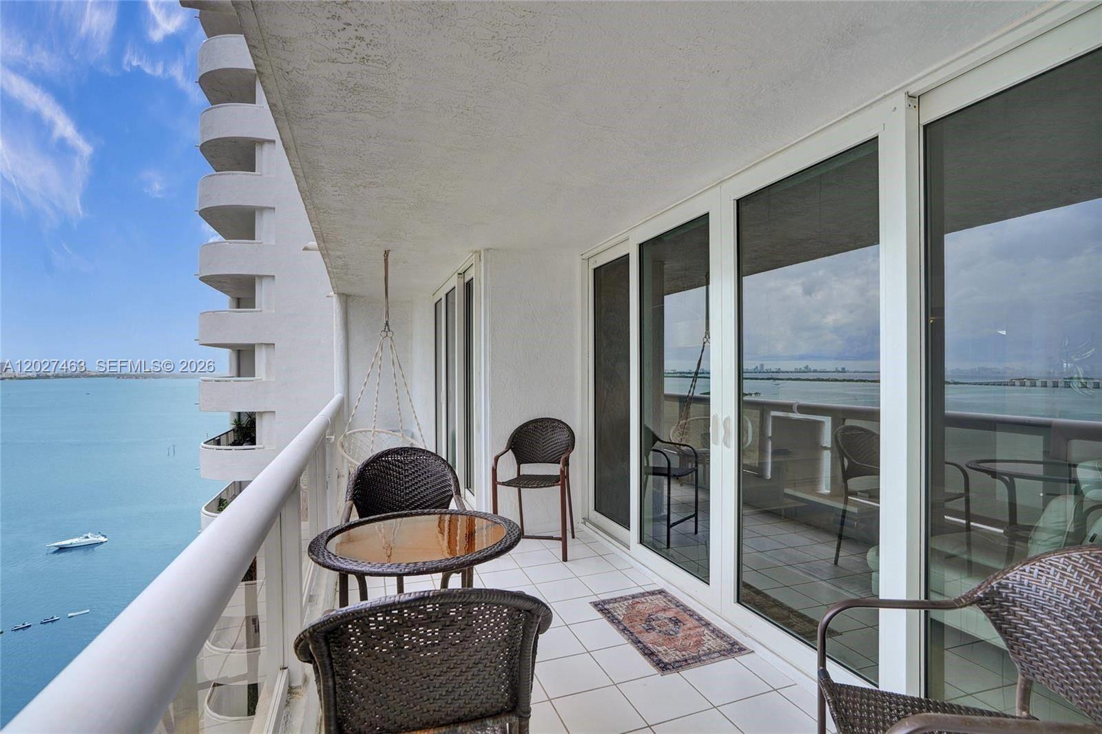 A balcony with wicker furniture overlooks a large body of water — 1717 N Bayshore Dr # 2440, Miami FL 33132, MIAMI, FL