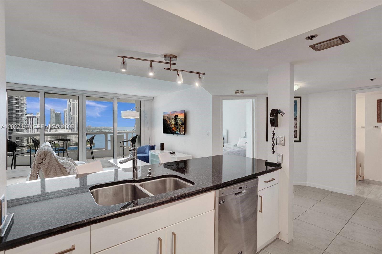 A kitchen with black granite countertops overlooks a living area with a balcony and view — 1717 N Bayshore Dr # 2440, Miami FL 33132, MIAMI, FL