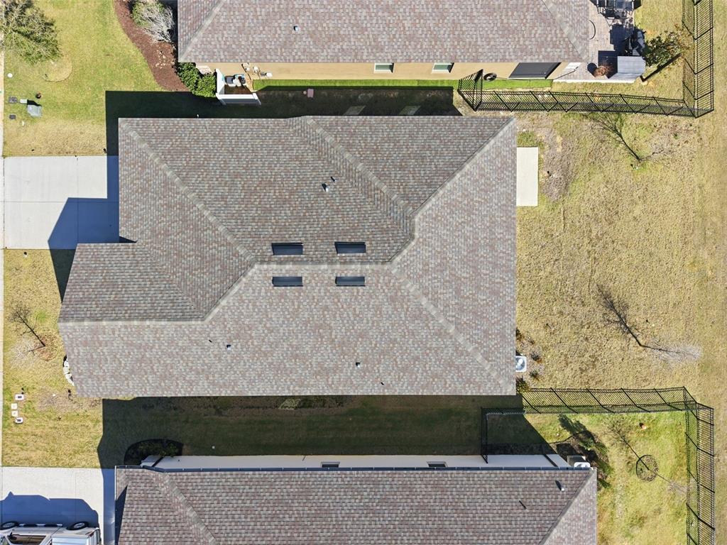 An aerial view shows the shingled roof of a house surrounded by neighboring properties — 1797 SUNDANCE CHASE ROAD, MINNEOLA, FL