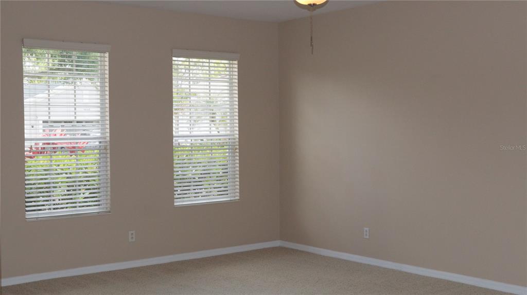 An empty room with beige walls, carpeted flooring, and two windows with white blinds — 2552 HOBBLEBRUSH DRIVE, NORTH PORT, FL