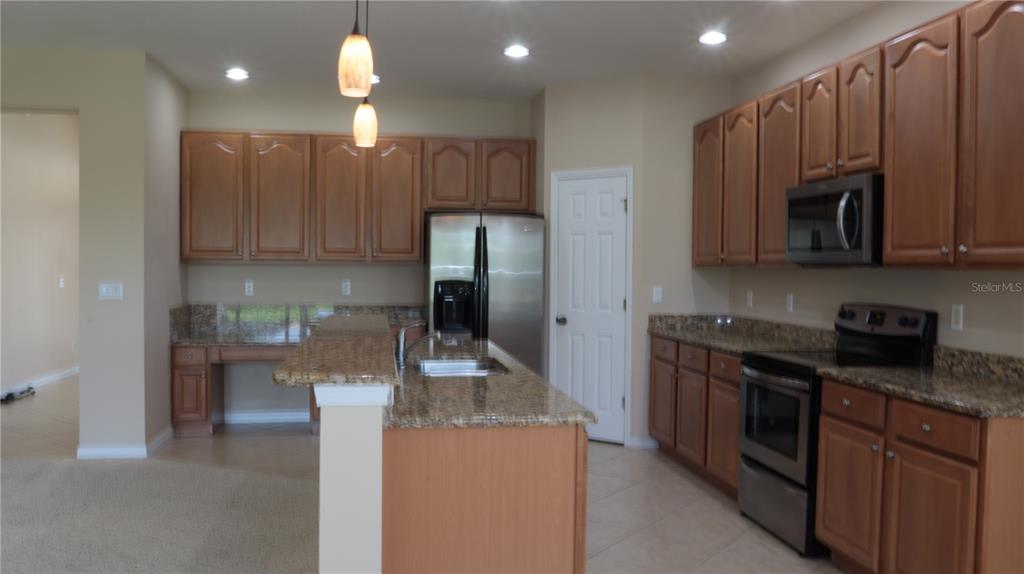 A kitchen features wood cabinets, granite countertops, stainless steel appliances, and a central island — 2552 HOBBLEBRUSH DRIVE, NORTH PORT, FL