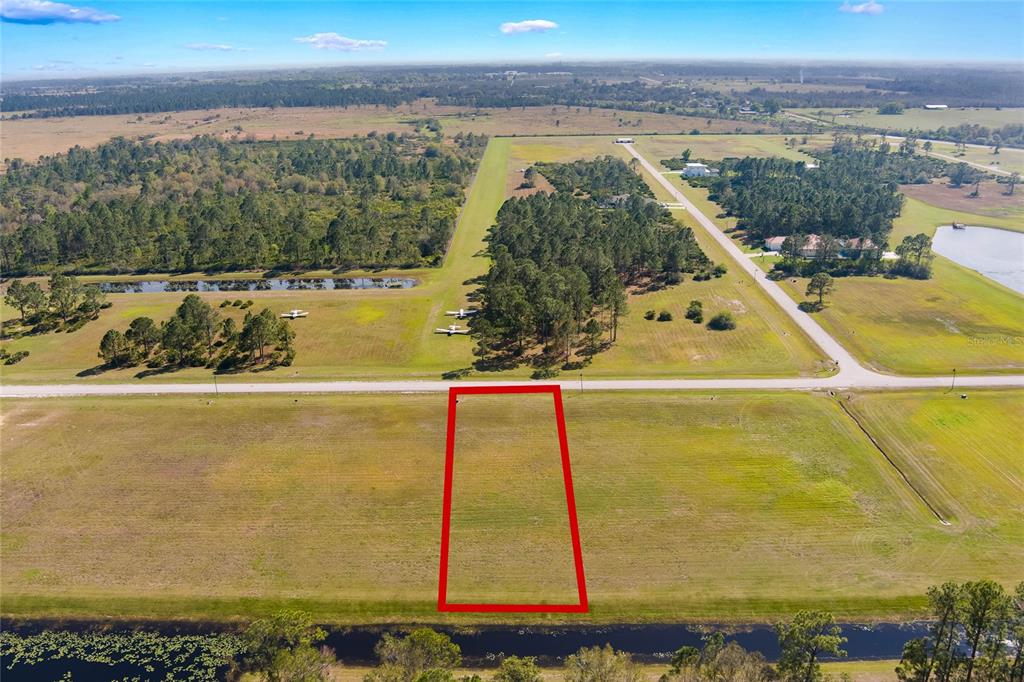 An aerial view shows a rectangular plot of land outlined in red near a runway — 4540 LINDBERGH            LOT 94 DRIVE, FROSTPROOF, FL