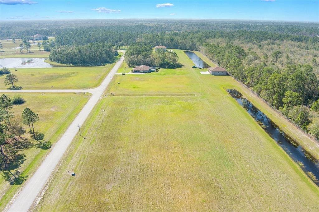 An aerial view shows a large, grassy lot with a house, detached garage, and pond — 4540 LINDBERGH            LOT 94 DRIVE, FROSTPROOF, FL
