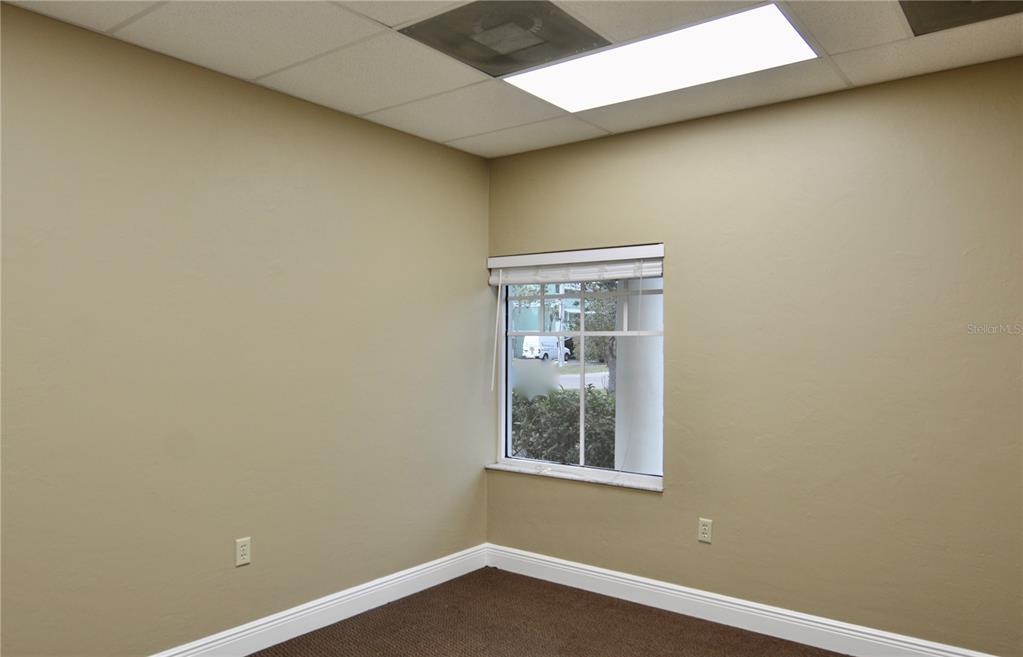 An empty office with beige walls, brown carpet, a window, and a drop ceiling — 2496 CARING WAY UNIT B, PORT CHARLOTTE, FL