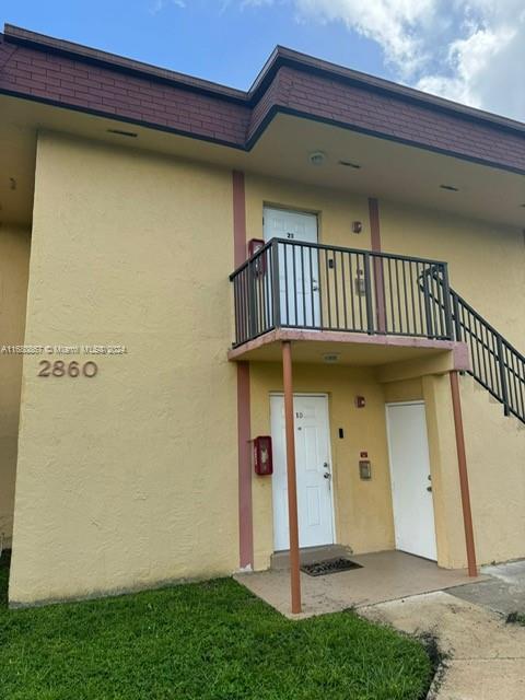 A two-story stucco apartment building features a second-floor balcony and two ground-level entry doors — 2860 NW 55th Ave # 2D, Lauderhill FL 33313, LAUDERHILL, FL