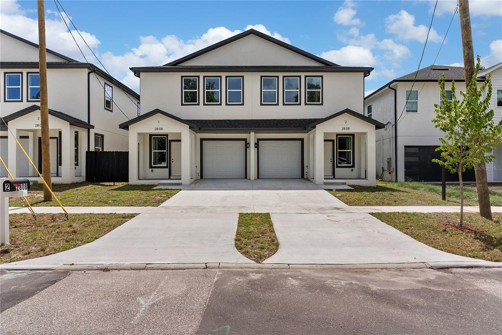 A two-story duplex with white siding, dark trim, and two attached garages — 2806 N 29TH STREET UNIT 1, TAMPA, FL