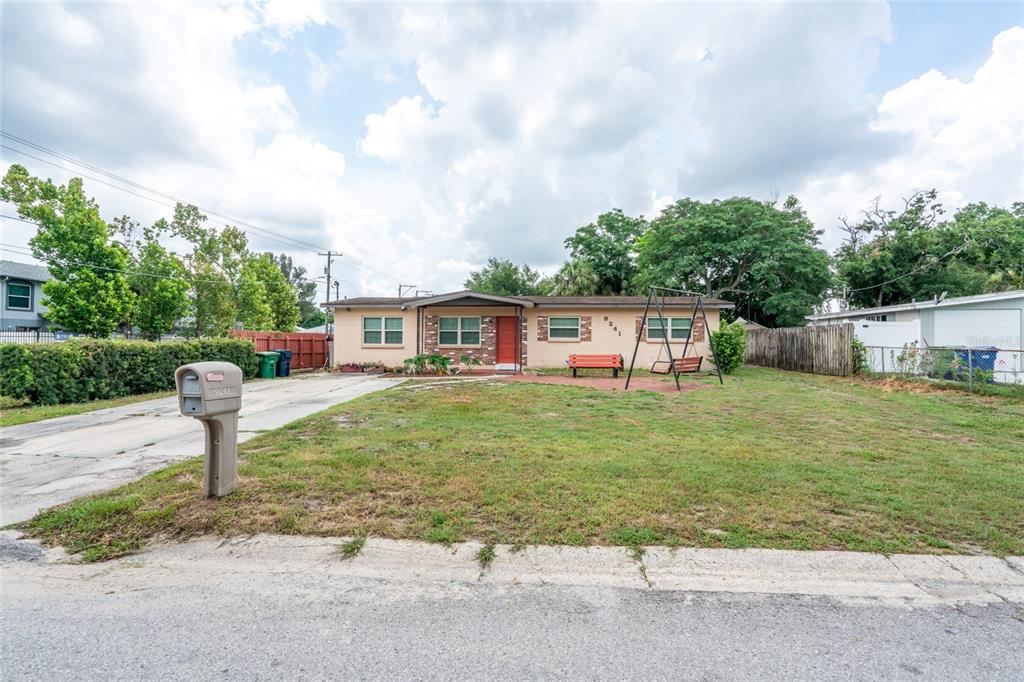 A single-story house with a red door, a front yard, and a swing set — 9241 N 52ND STREET, TAMPA, FL