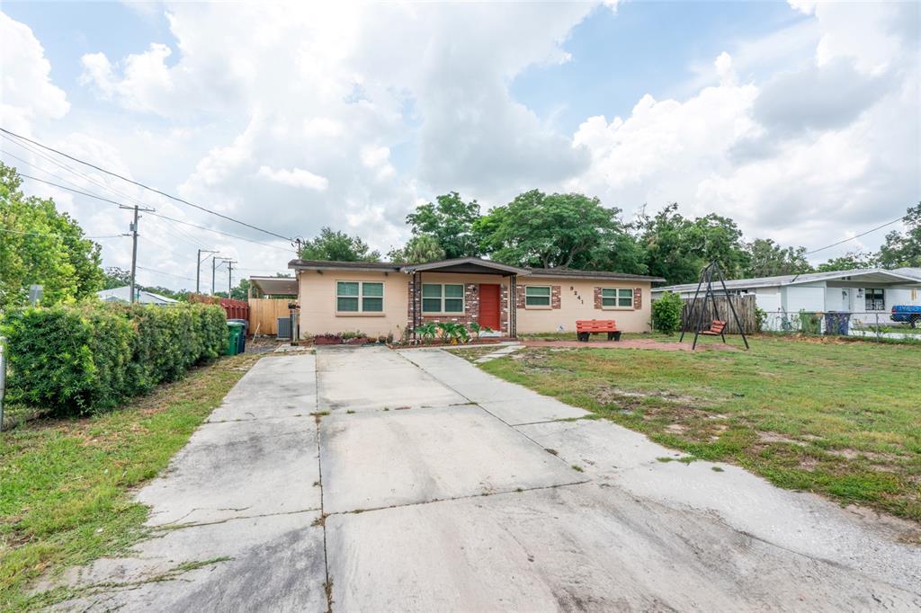 A single-story house with a concrete driveway, red front door, and a front yard — 9241 N 52ND STREET, TAMPA, FL