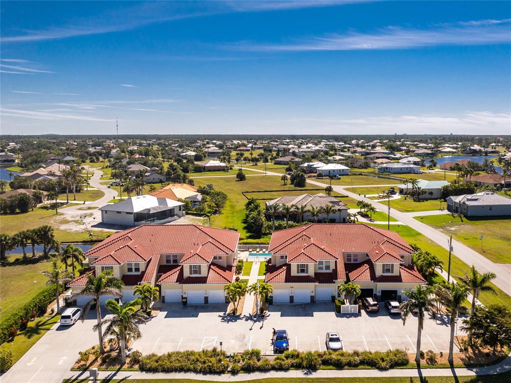 An aerial view shows two adjacent townhouses with red tile roofs and a shared pool — 17200 ACAPULCO ROAD UNIT 123, PUNTA GORDA, FL