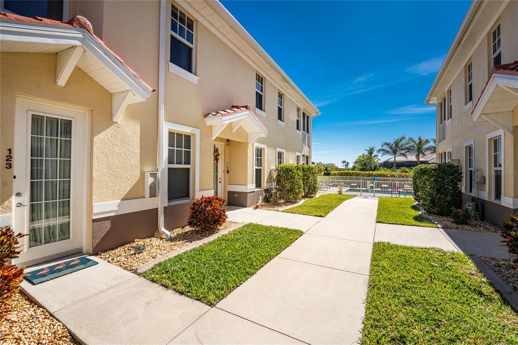 An exterior view of two-story townhomes with a sidewalk leading toward a swimming pool — 17200 ACAPULCO ROAD UNIT 123, PUNTA GORDA, FL