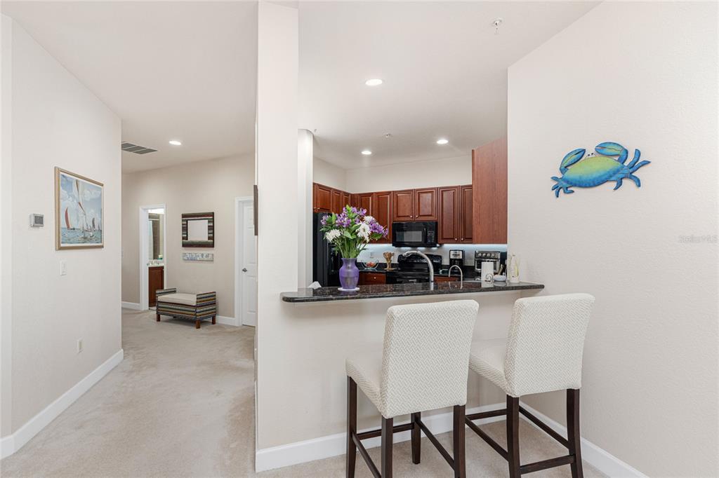 A kitchen with dark wood cabinets and a breakfast bar with two upholstered stools — 17200 ACAPULCO ROAD UNIT 123, PUNTA GORDA, FL
