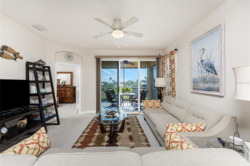 A living room features a beige sectional sofa, a glass coffee table, and a sliding door — 17200 ACAPULCO ROAD UNIT 123, PUNTA GORDA, FL