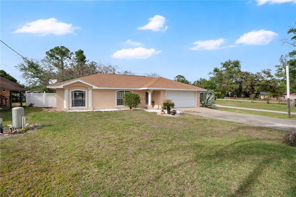 A single-story house with a tan stucco exterior, a brown roof, and a two-car garage — 18 ANGELES ROAD, DEBARY, FL