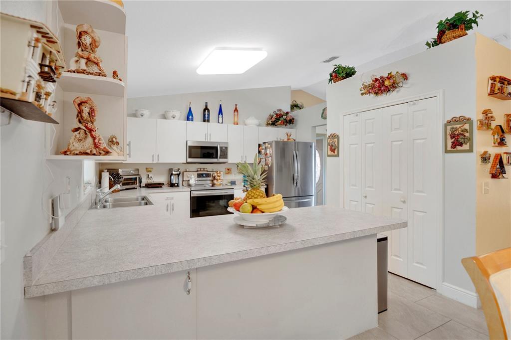 A kitchen features white cabinets, stainless steel appliances, and a peninsula with a fruit bowl — 18 ANGELES ROAD, DEBARY, FL