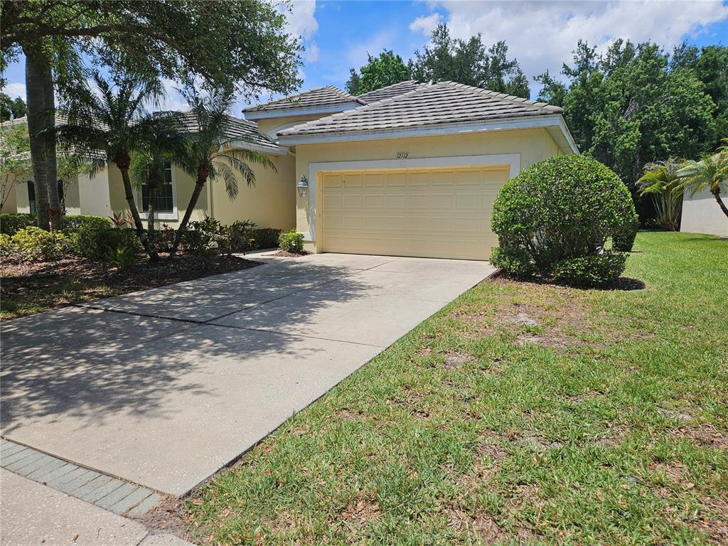 A single-story house with a beige exterior, a two-car garage, and a concrete driveway — 12112 MAPLE RIDGE DRIVE, PARRISH, FL