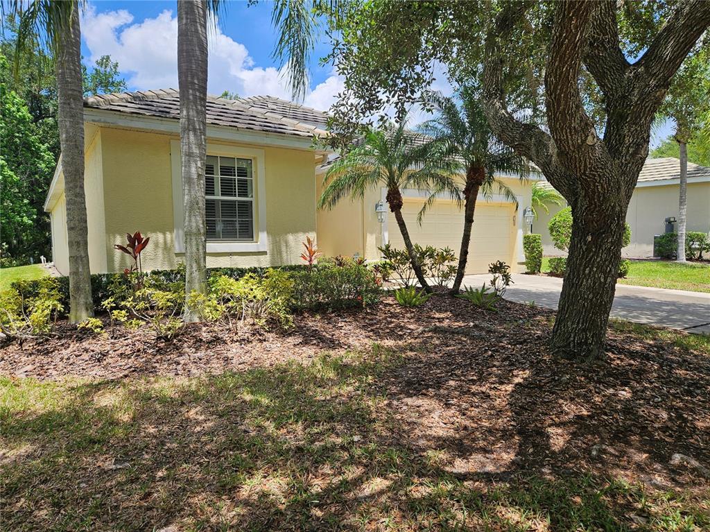 A yellow single-story house features a two-car garage, palm trees, and a landscaped front yard — 12112 MAPLE RIDGE DRIVE, PARRISH, FL