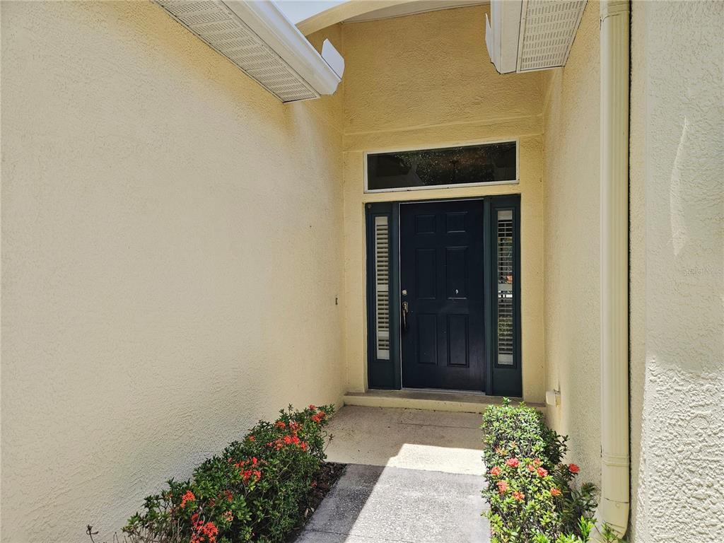 A dark front door with sidelights and a transom window sits at the home's entrance — 12112 MAPLE RIDGE DRIVE, PARRISH, FL