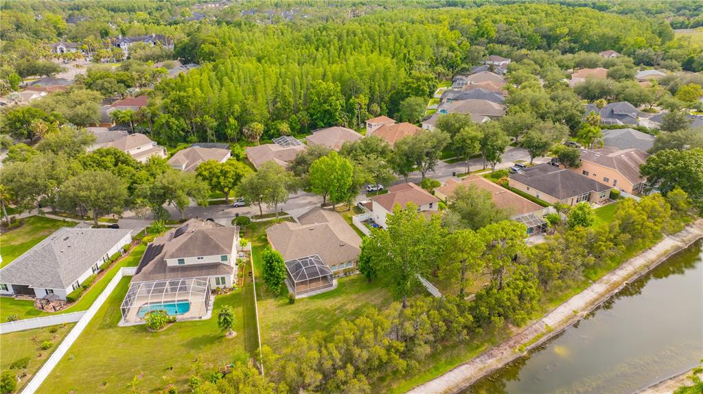 An aerial view shows a suburban neighborhood with houses, swimming pools, and a nearby canal — 6028 CATLIN DRIVE, TAMPA, FL