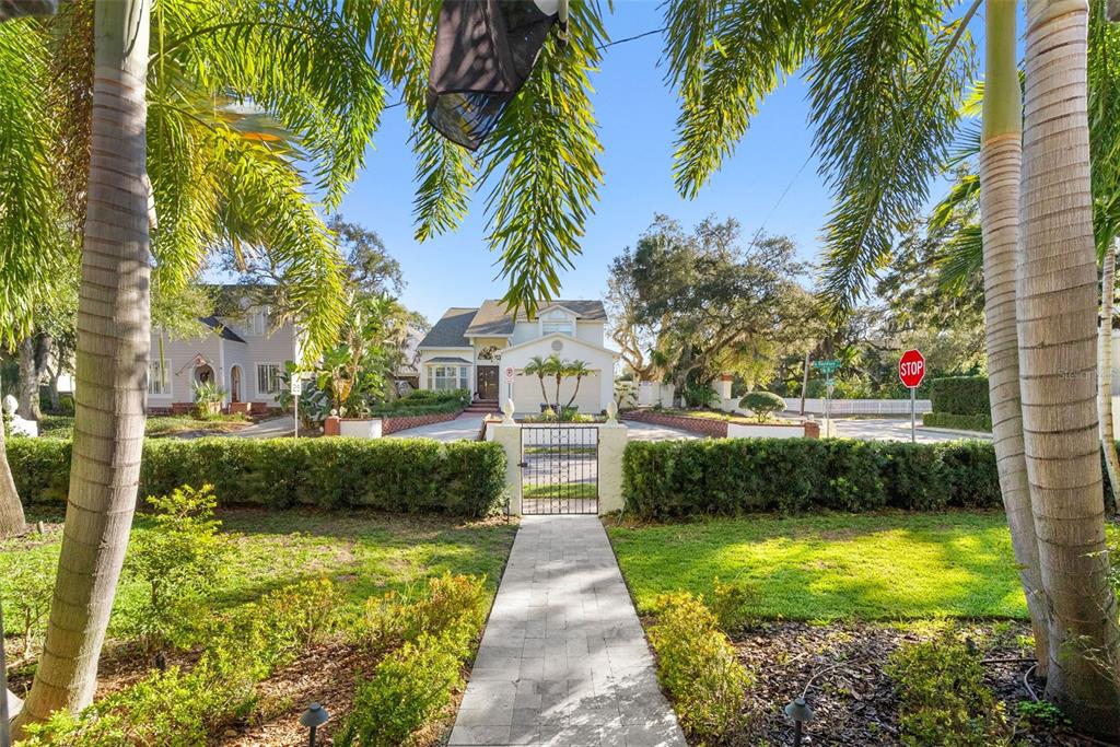 A paved walkway leads through a gate to a two-story house with palm trees — 2943 W BAYSHORE COURT, TAMPA, FL