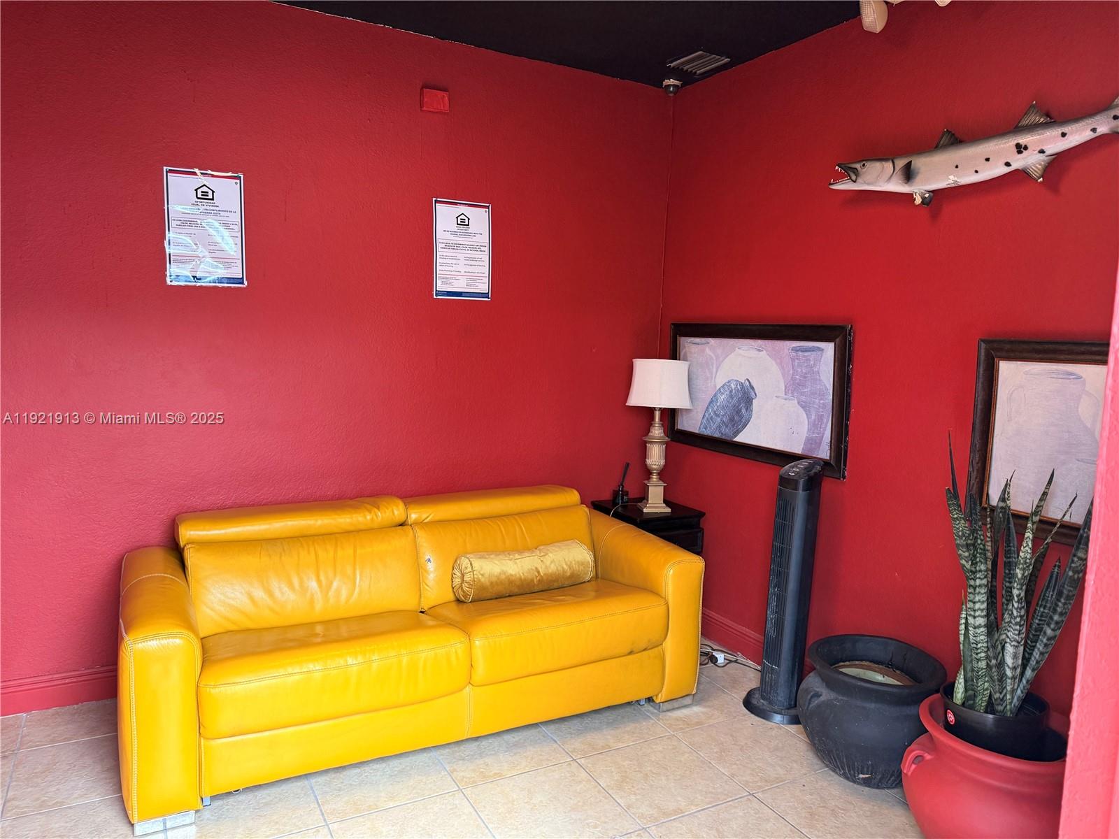 A bright yellow leather sofa sits against a red wall in this room — 16205 SW 117th Ave # 3, Miami FL 33177, MIAMI, FL