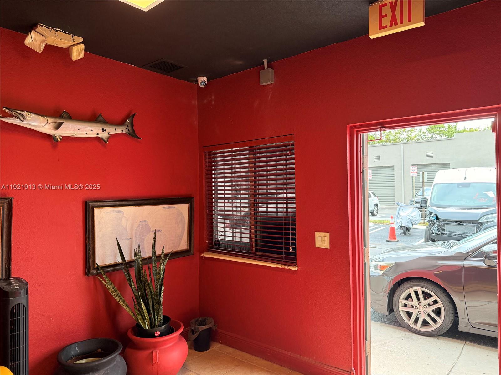 A room with red walls, a mounted fish, a window with blinds, and an open doorway — 16205 SW 117th Ave # 3, Miami FL 33177, MIAMI, FL