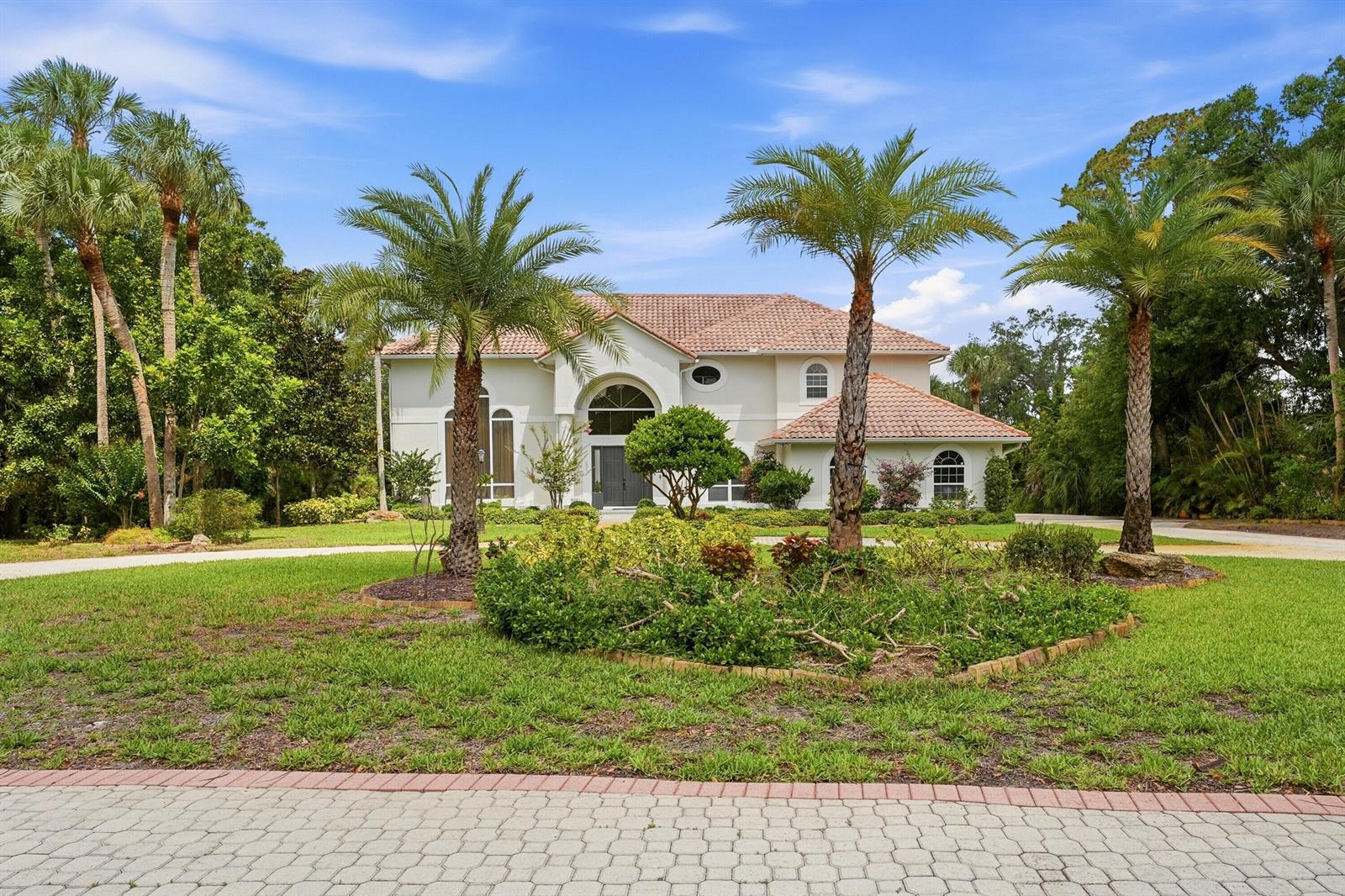 A two-story white house with a tile roof sits behind a landscaped palm tree garden — 12765 Roseland Road, Sebastian FL 32958, SEBASTIAN, FL