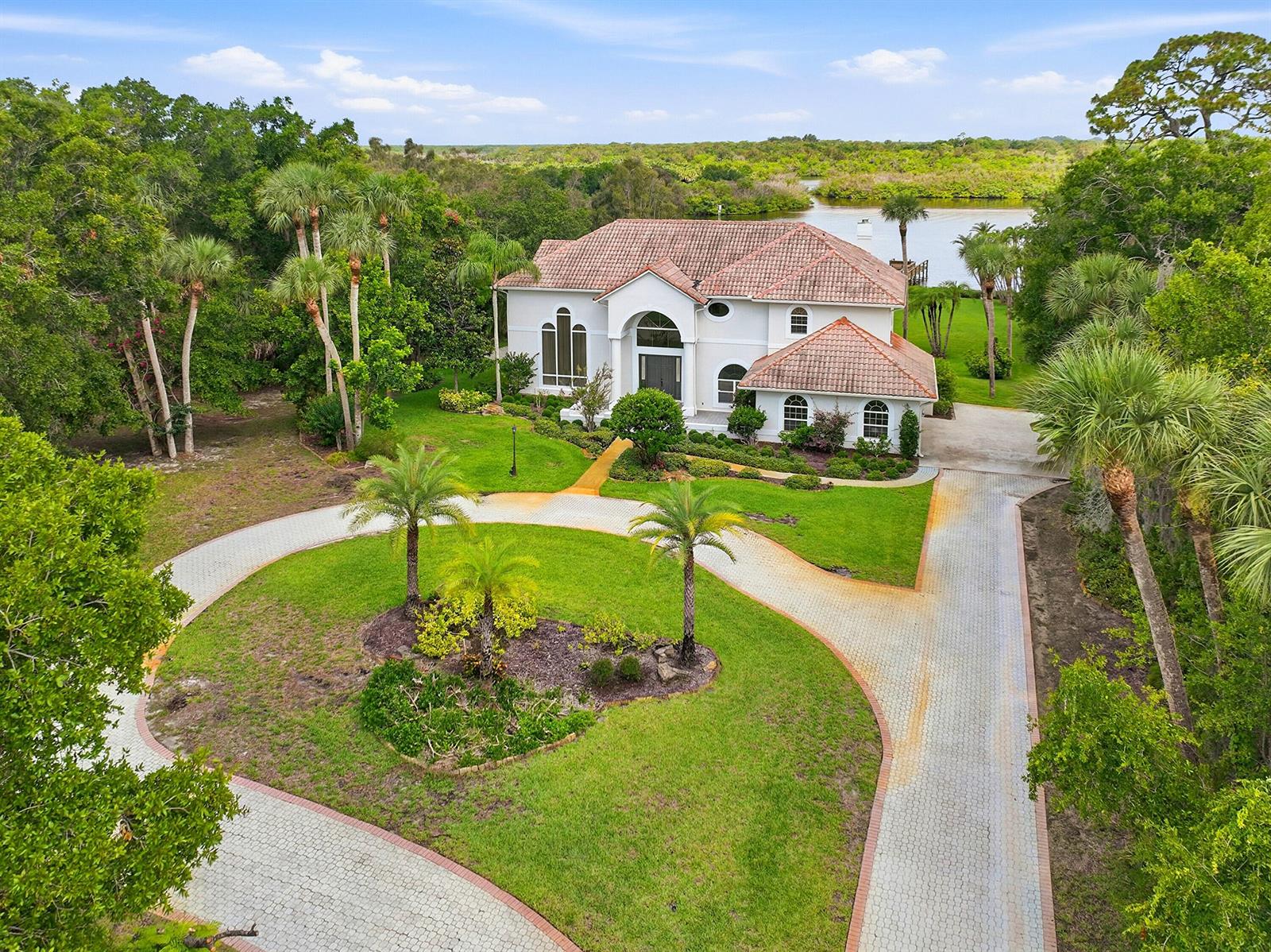 The exterior of a house features a paved walkway, two large columns, and a double door — 12765 Roseland Road, Sebastian FL 32958, SEBASTIAN, FL