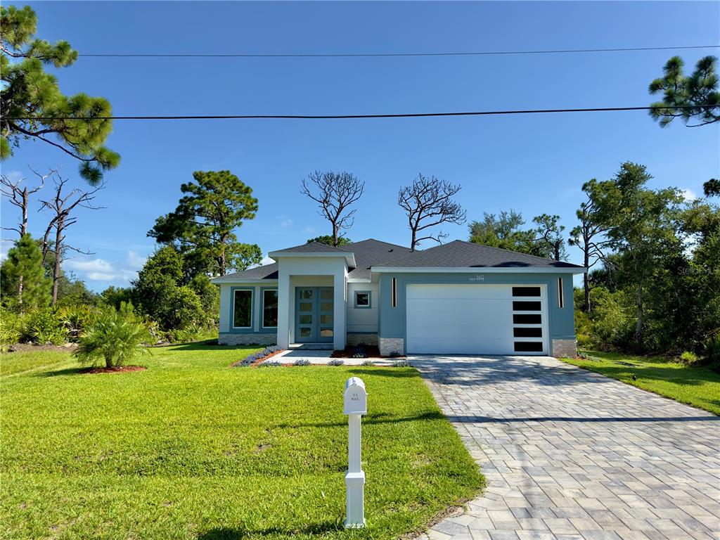 A single-story house with light blue siding, a white garage door, and a paved driveway — 140 LINDA LEE DRIVE, ROTONDA WEST, FL