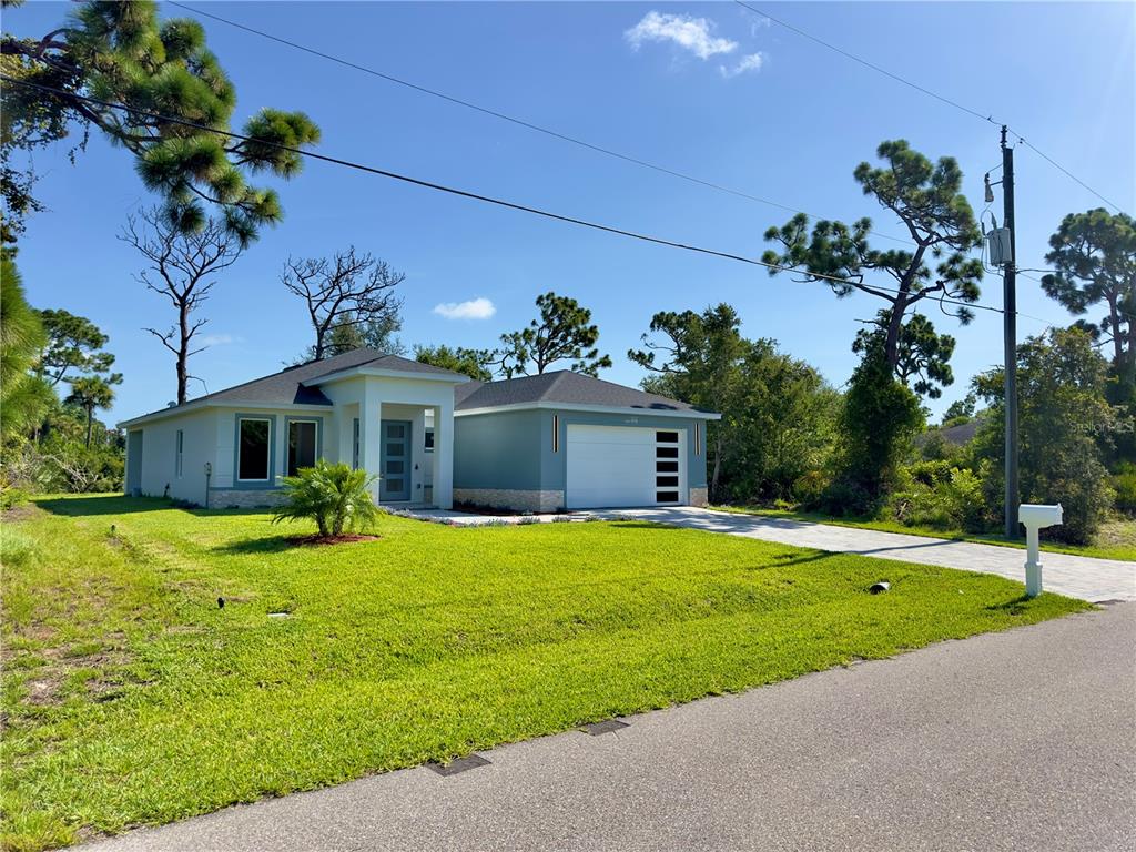 A modern, light blue single-story house with a two-car garage and a paved driveway — 140 LINDA LEE DRIVE, ROTONDA WEST, FL