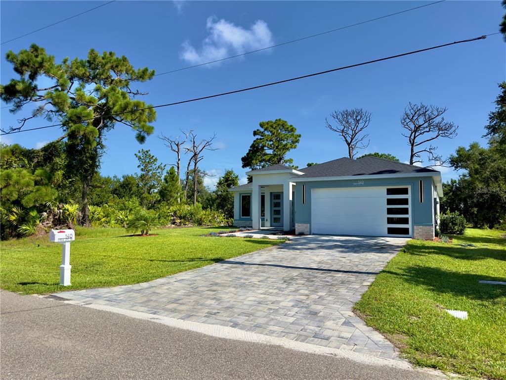 A single-story house with a blue exterior, white garage door, and a paved driveway — 140 LINDA LEE DRIVE, ROTONDA WEST, FL
