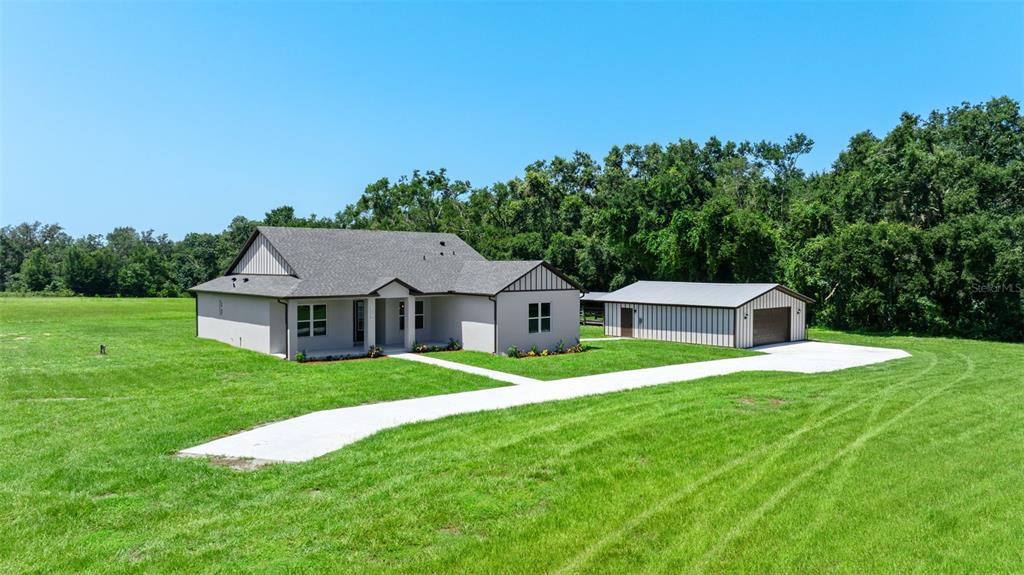 A single-story house with a detached garage sits on a large, grassy lot — 13219 NEWGENT ROAD, SAN ANTONIO, FL