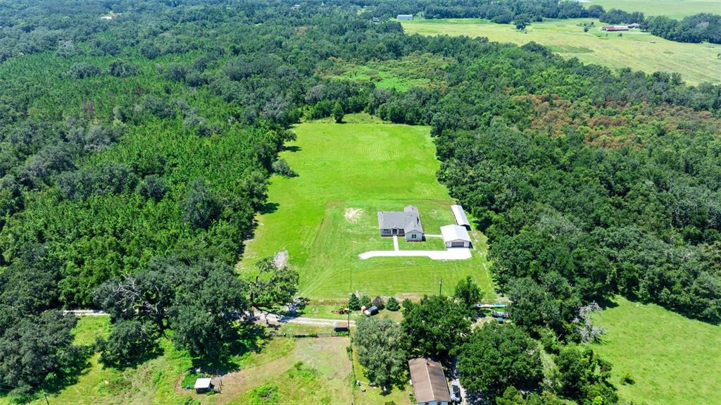 An aerial view shows a house and detached garage situated on a large, grassy lot — 13219 NEWGENT ROAD, SAN ANTONIO, FL