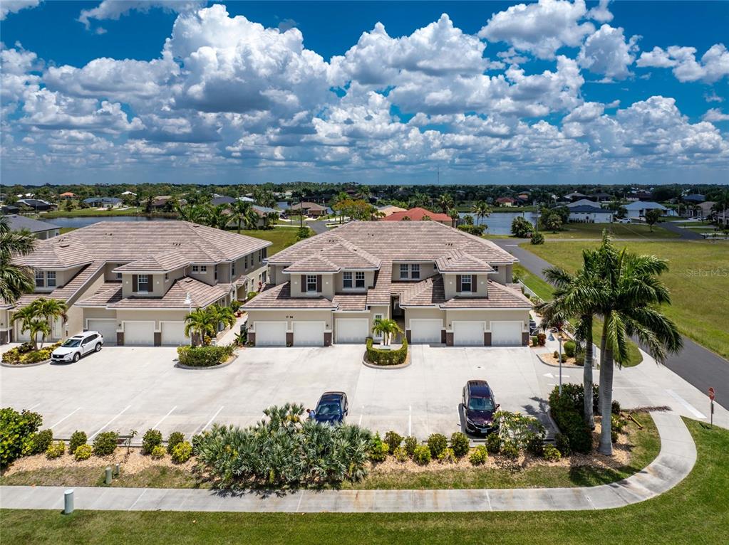 An aerial view shows two multi-unit residential buildings with attached garages and a parking lot — 17094 ACAPULCO ROAD UNIT 321, PUNTA GORDA, FL