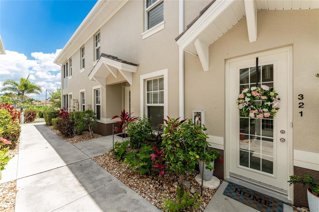 The exterior of a two-story beige townhouse features a front door with a floral wreath — 17094 ACAPULCO ROAD UNIT 321, PUNTA GORDA, FL