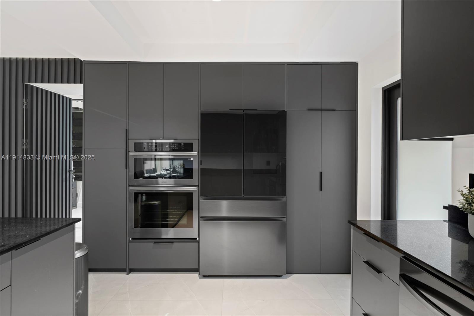 A modern kitchen features dark gray cabinetry, stainless steel appliances, and black granite countertops — 1101 N 14th Ave, Hollywood FL 33020, HOLLYWOOD, FL