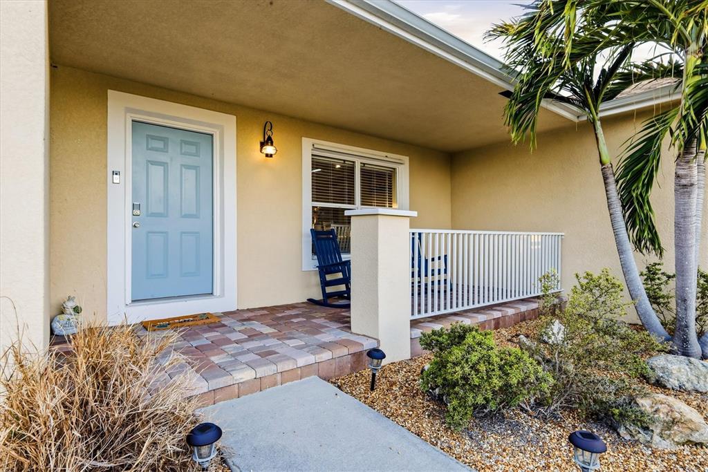 A light blue front door opens onto a paved porch with a white railing — 10379 CALUMET BOULEVARD, PORT CHARLOTTE, FL