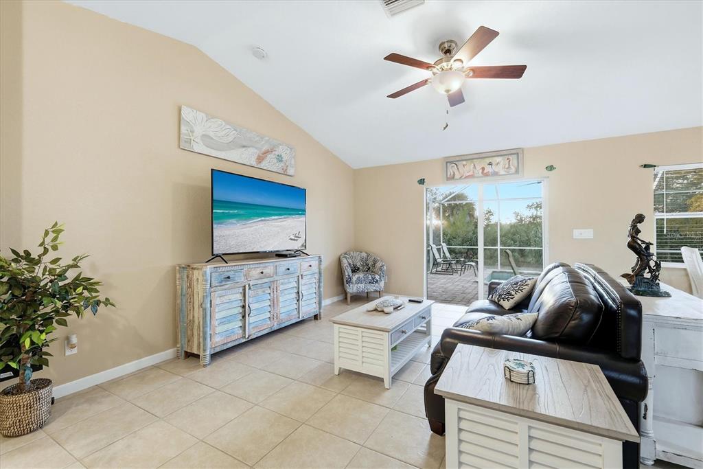This open-concept living area features tile flooring, a leather sofa, and a kitchen with barstools — 10379 CALUMET BOULEVARD, PORT CHARLOTTE, FL
