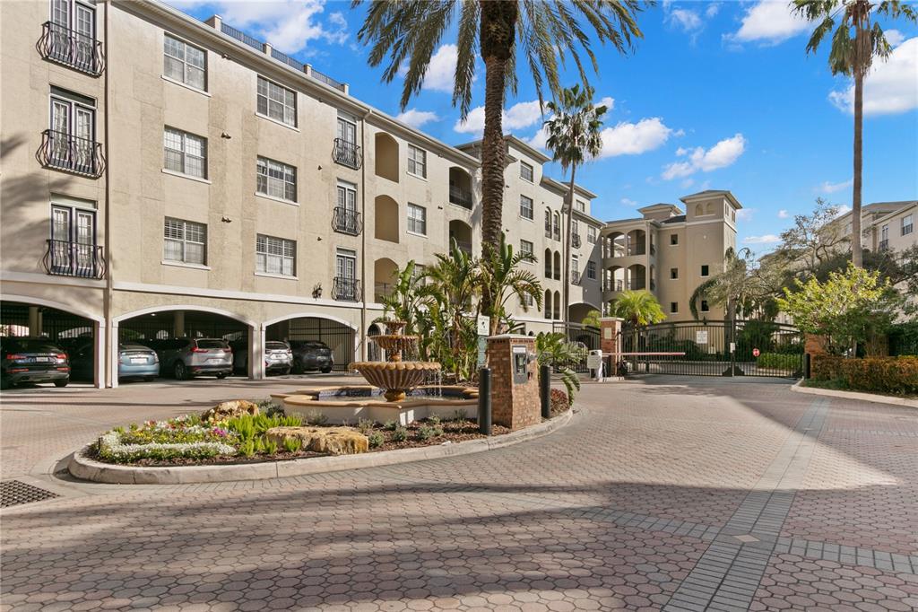 A multi-story apartment building features a central fountain, palm trees, and a gated entrance — 501 KNIGHTS RUN AVENUE UNIT 1310, TAMPA, FL
