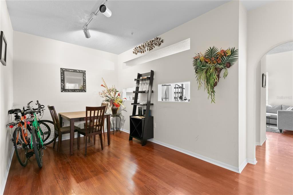 A dining room with hardwood floors, a wooden table, chairs, and a black shelving unit — 501 KNIGHTS RUN AVENUE UNIT 1310, TAMPA, FL