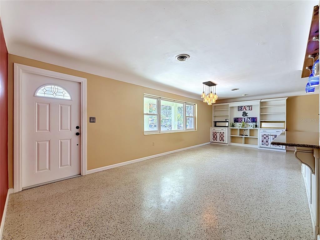A room with tan walls, a white front door, terrazzo flooring, and built-in shelving units — 5163 60TH WAY N, KENNETH CITY, FL