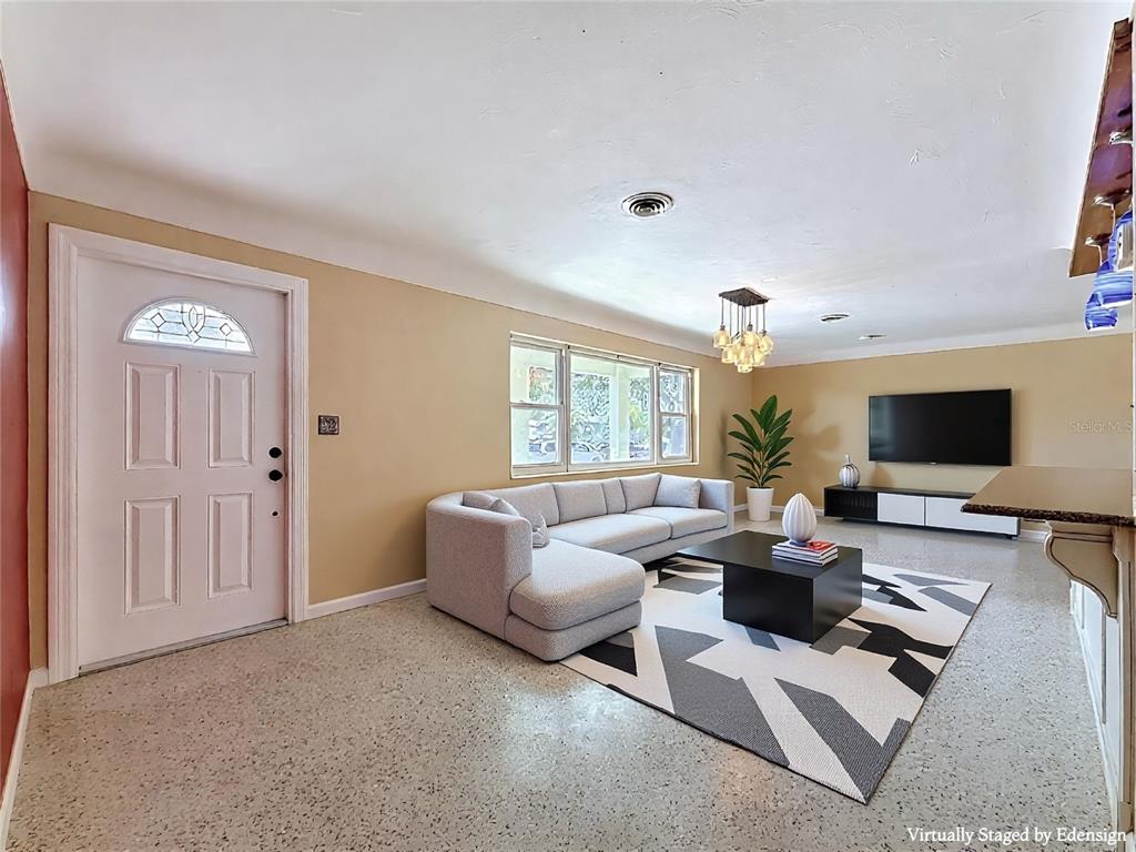 A living room features a sectional sofa, a geometric rug, and a wall-mounted television — 5163 60TH WAY N, KENNETH CITY, FL