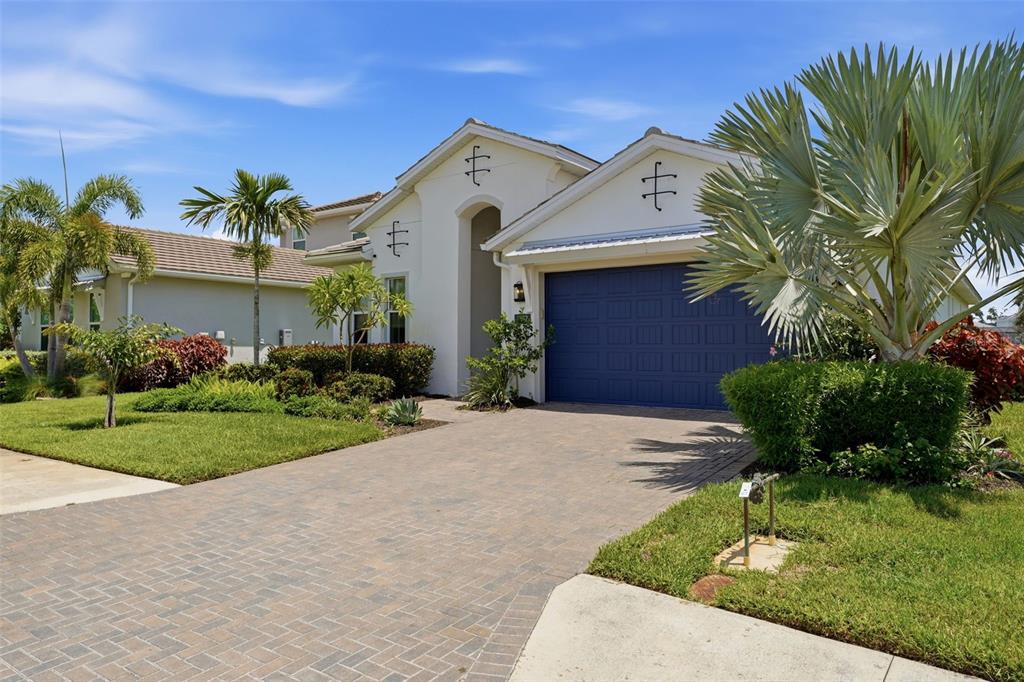 A single-story house with a blue garage door, white stucco exterior, and a paved driveway — 7857 REDONDA LOOP, LAKEWOOD RANCH, FL