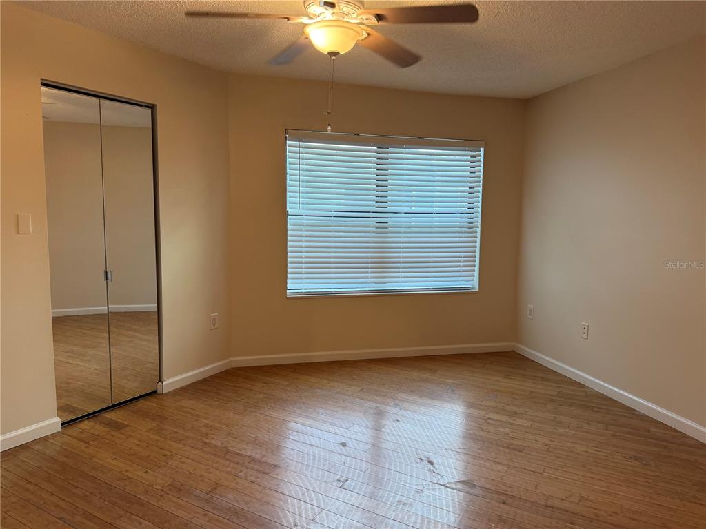 An empty bedroom features light-colored walls, wood-look flooring, a ceiling fan, and mirrored closet doors — 3816 SOUTHPOINTE DRIVE UNIT U2, ORLANDO, FL