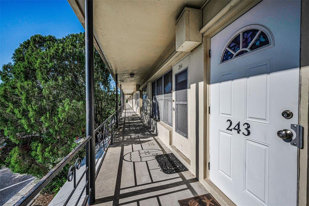 An exterior walkway features a white door numbered 243 with a decorative stained glass window — 4051 58TH STREET N UNIT 243, KENNETH CITY, FL