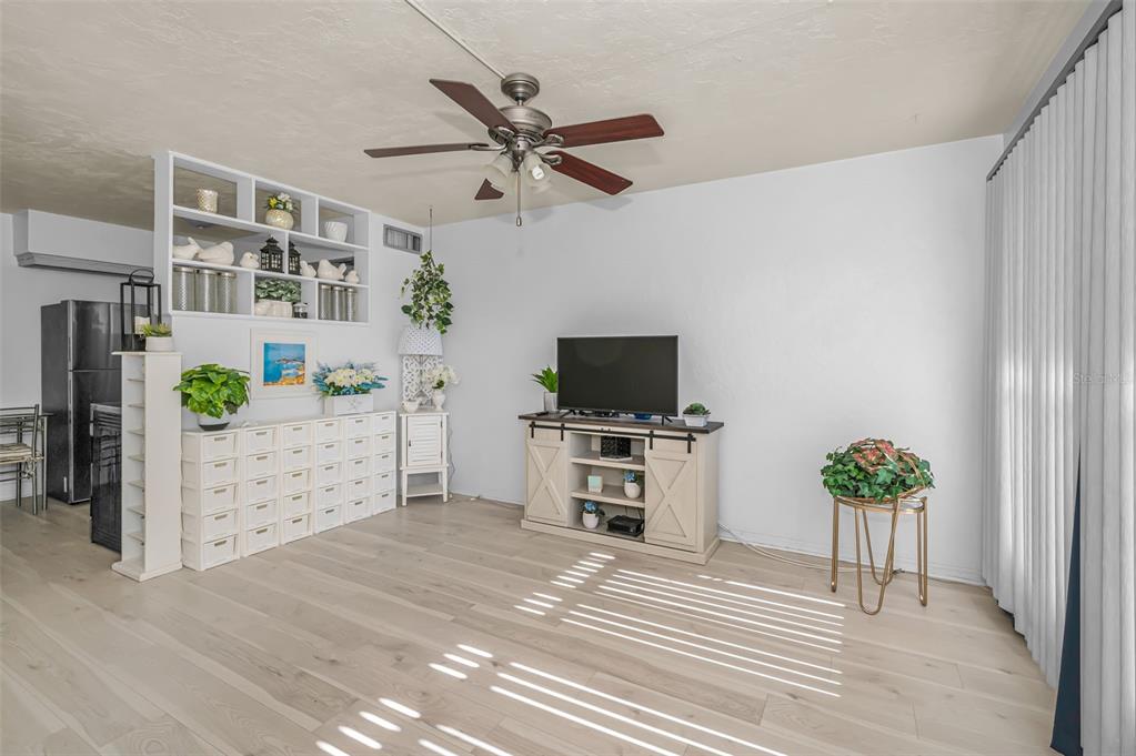 A living room features light wood flooring, a ceiling fan, and a white media console — 4051 58TH STREET N UNIT 243, KENNETH CITY, FL