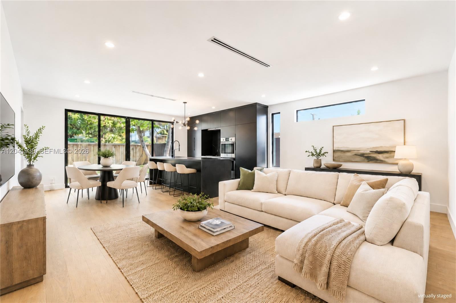 A modern open-concept living and dining area features a black kitchen island and light flooring — 227 NW 39th St, Miami FL 33127, MIAMI, FL
