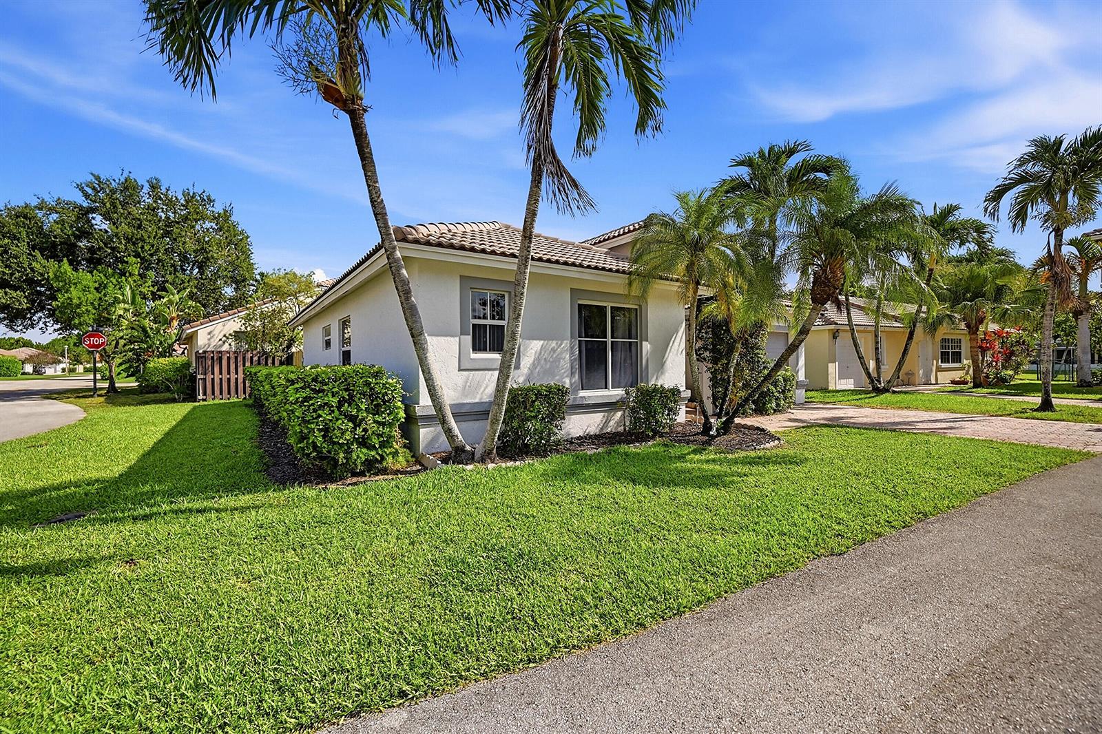 A single-story house with a beige exterior, palm trees, and a green lawn — 1852 Capeside Circle, Wellington FL 33414, WELLINGTON, FL