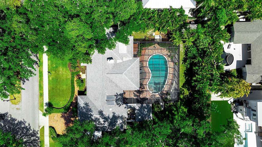 An aerial view shows a house with a screened-in pool surrounded by lush green trees — 1714 SOUTH DRIVE, SARASOTA, FL