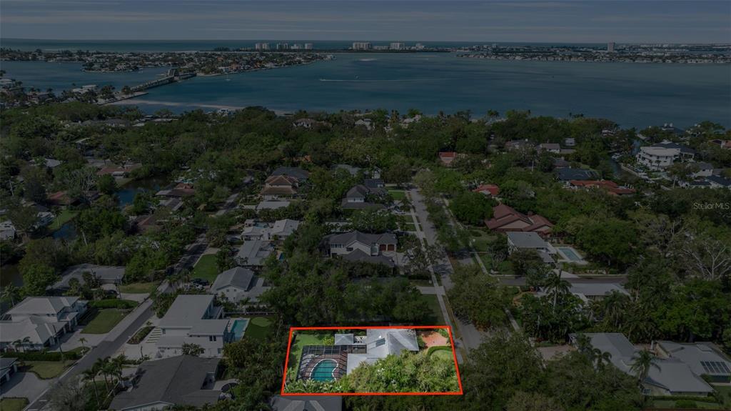 An aerial view of a residential property with a pool and lush landscaping near water — 1714 SOUTH DRIVE, SARASOTA, FL